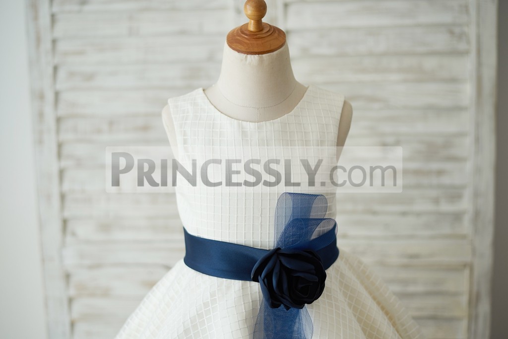 Scoop neckline, sleeveless bodice with a navy blue belt & flower